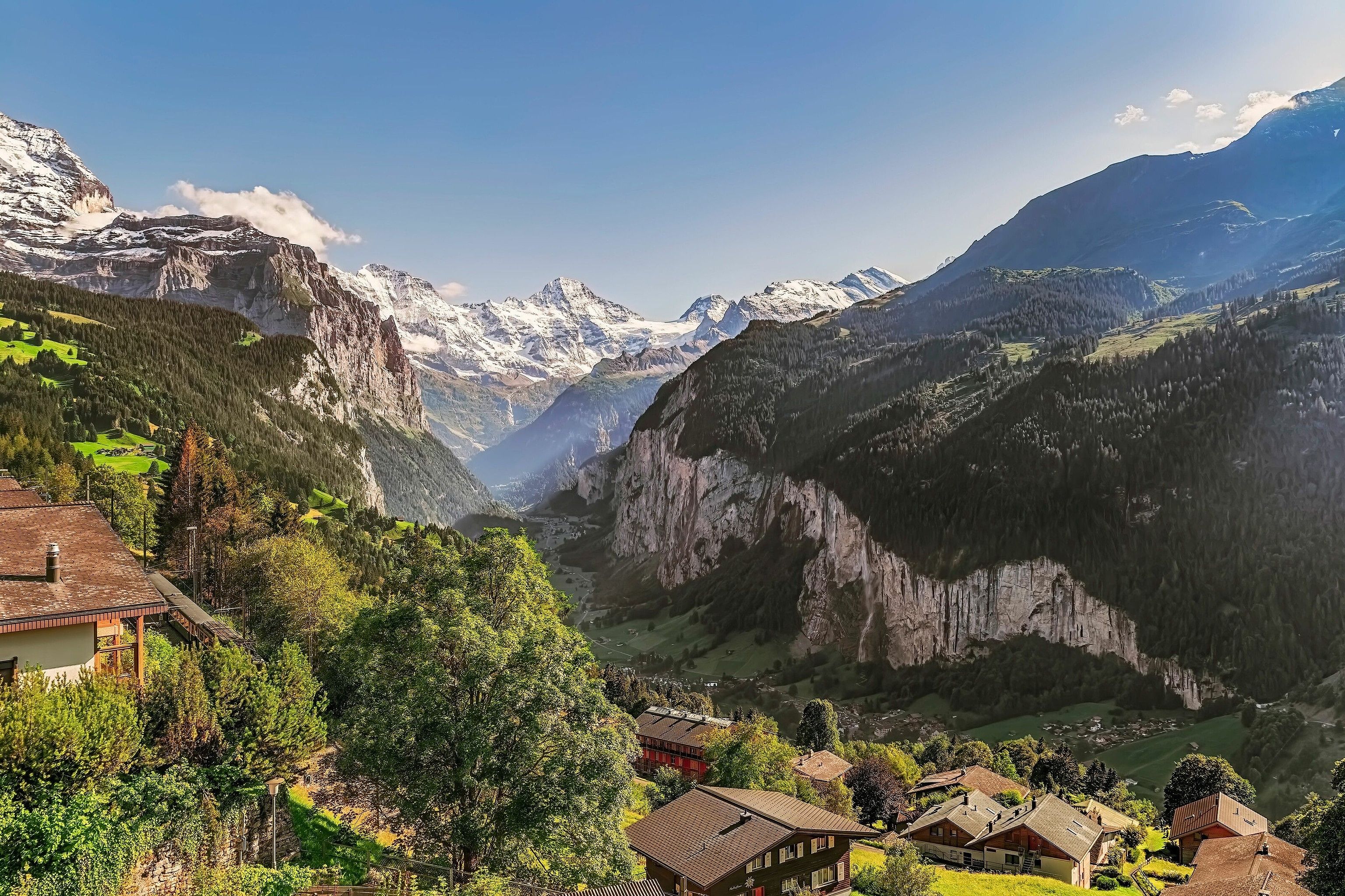 A green valley runs away into steep snowy mountains.